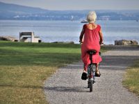 Femme âgée en vélo sur chemin.