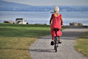 Femme âgée en vélo sur chemin.